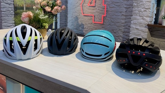 Vier moderne Helme liegen auf einem Tisch im MDR um 4-Studio