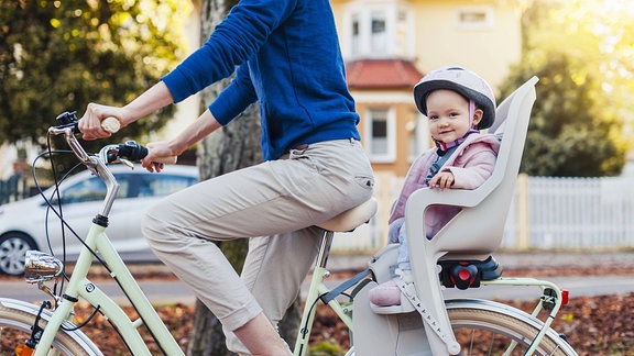Eine junge Frau auf einem Fahrrad mit einem Kind im Kindersitz