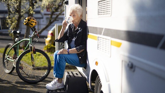 Rentnerin vor ihrem Wohnwagen