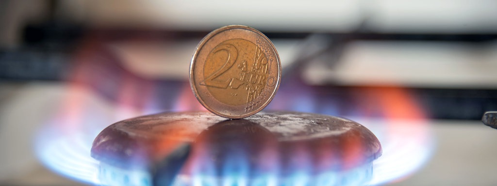 Ein 2-Euro-Stück steht auf dem Kochfeld eines Gasherdes.