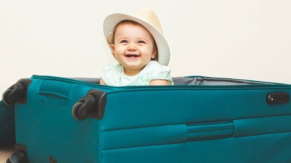 Ein Baby sitzt in einem Reisekoffer.