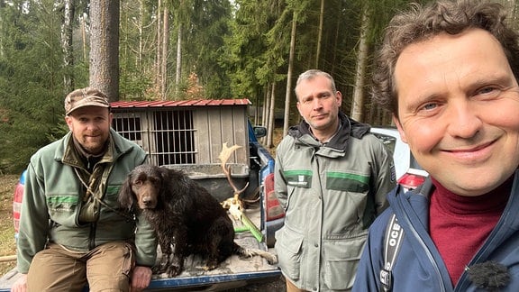 Drei Männer mit Hund in einem Wald