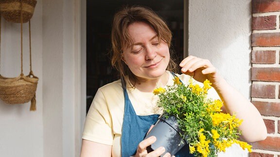 Eine Frau hält einen Blumentopf in den Händen.