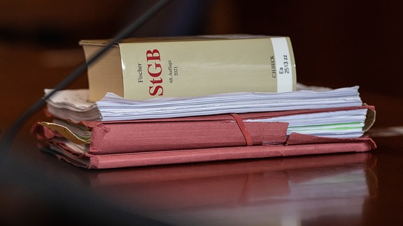 Das Strafgesetzbuch und Akten liegen aufeinem Tisch.