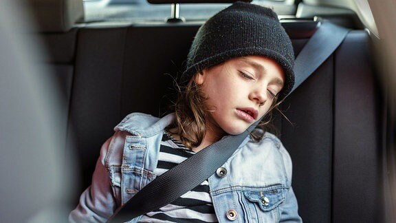 Ein Mädchen schläft auf der Rückbank eines Autos 