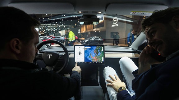 Zwei Männer sitzen in einem Tesla Model 3 Elektroauto.