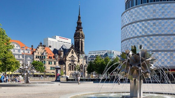 Richard-Wagner-Platz mit Pusteblumen-Brunnen und der "Blechbüchse", dahinter die Evangelisch-Reformierte Kirche am Tröndlinring