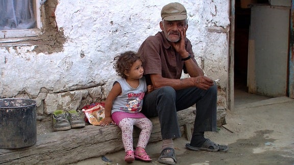 Ein Großvater mit seinem Enkelkind vor ihrer Hütte