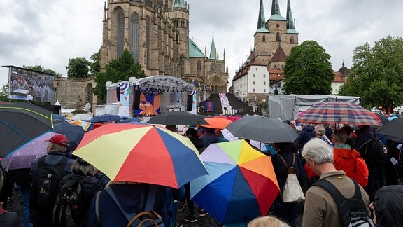 Gläubige und Besucher des 103. Deutschen Katholikentags verfolgen den Fronleichnams-Gottesdienst auf dem Domplatz Erfurt.