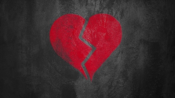 Ein rotes, zebrochenes Herz auf schwarzem Hintergrund.