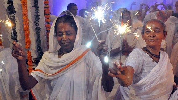 Indische Frauen tragen Wunderkerzen.