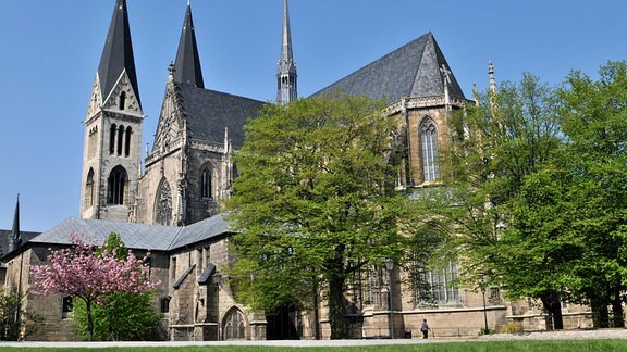 Blick auf den Dom zu Halberstadt: ein großer, mittelalterlicher Kirchenbau mit zwei Türmen an der Front und einem halbrunden Abschluss.