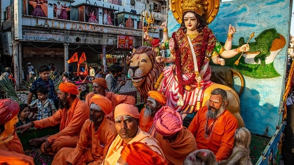 Eine Gruppe von Sadhus in safranfarbenen Gewändern sitzt um ein verziertes Idol von Bharat Mata (Mutter Indiens)