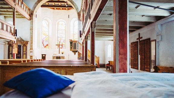 Bett mit Bettwäsche in einer Kirche