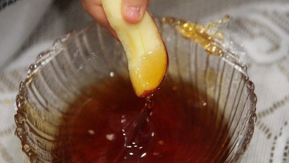 Kinder tauchen Äpfel in eine Schale mit Honig
