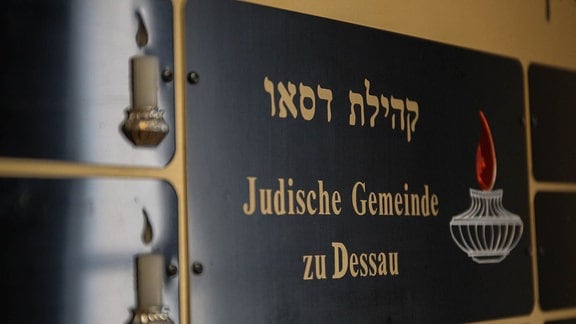 Eine Wandtafel mit elektrischen Lichtern in Form einer Kerze und der Aufschrift: Jüdische Gemeinde zu Dessau