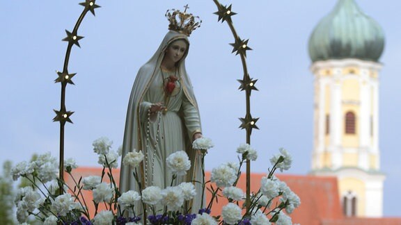 Gläubige tragen bei der Wallfahrtskirche Maria Vesperbild bei der Lichterprozession eine Marienstatue.
