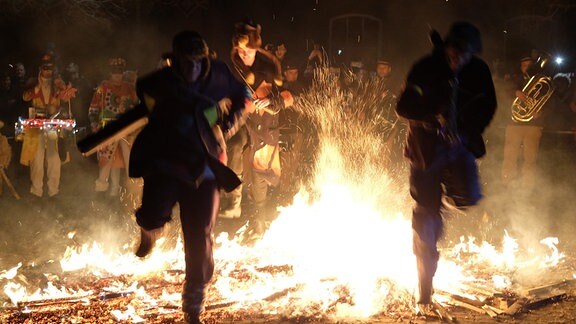Teilnehmer der Spergauer Lichtmess springen über ein Feuer. Die Spergauer Lichtmess ist ein uralter Brauch, der am ersten Sonntag nach Maria Lichtmess gefeiert wird.