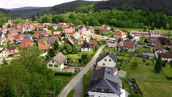 Eine Ortschaft zwischen bewaldeten Hügeln