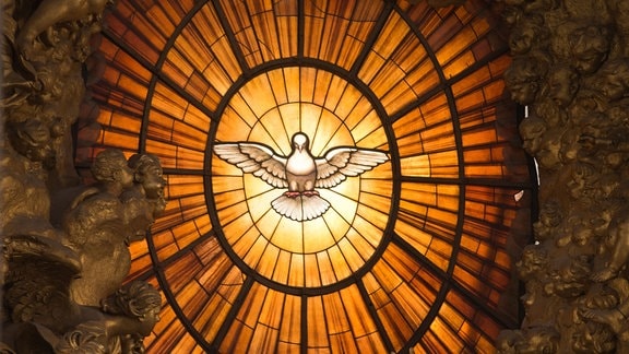 Ein Kirchenfenster mit einer Darstellung des Heiligen Geistes in Form einer Taube.