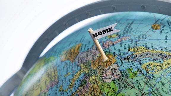Ein Fähnchen mit der Aufschrift "Home" steckt bei Deutschland auf einem Globus