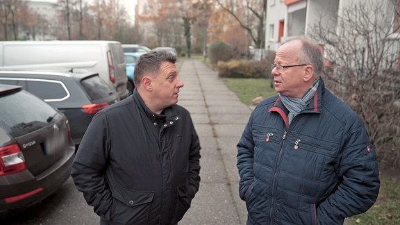 Reportage Tatortreiniger: Zwei Männer vor einem Neubaublock im Gespräch