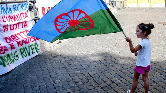 Beschreibung Kind mit der Roma-Flagge auf einer Antidiskriminierungs-Kundgebung in Rom