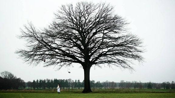 eine Frau steht an einem Baum