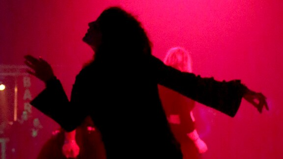 Schwarze Silhouette einer Frau beim Tanzen, getaucht in rotes Licht