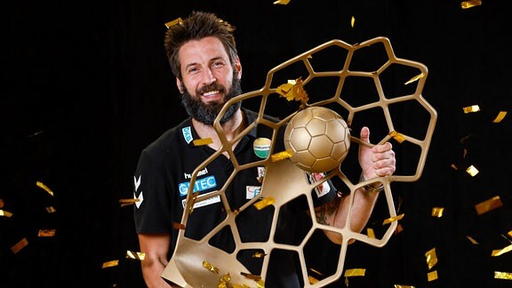 Handballtrainer des SC Magdeburg, Bennet Wiegert, jubelt mit einem Pokal