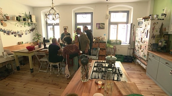 Menschen gemeinsam in einer Küche am Esstisch.