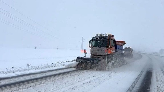 Räumfahrzeug schiebt Schnee auf Landstraße.