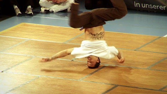 Ein Mann dreht sich auf seinem Kopf beim Breakdance.