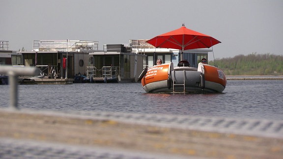 rundes Boot mit Sonnenschirm auf einem See.