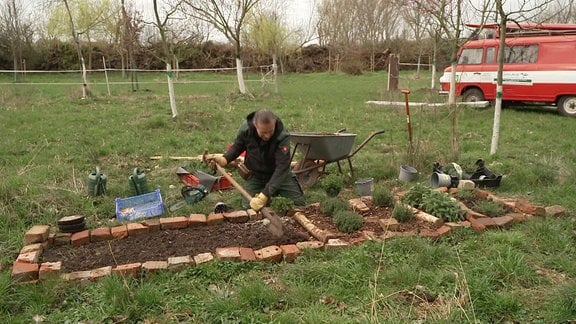Ein Mann bearbeitet ein Beet im Garten.