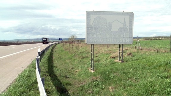 Verblichenes Schild neben der Autobahn weißt auf das Europa-Rosarium Sangerhausen hin.