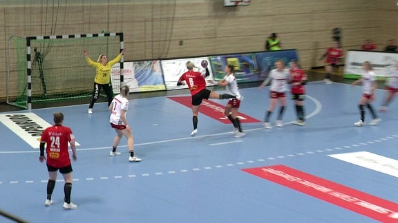 Handballspiel. Spielerin in rotem Trikot wirft Ball.