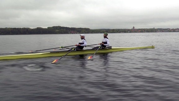 Zwei Sportler im Ruderboot auf einem See.