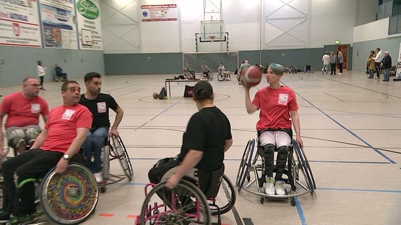 Sportler im Rollstuhl spielen Basketball.