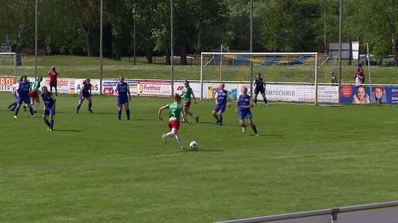 Eine Spielerin im grünen Trikot am Ball.
