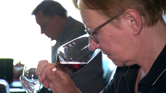 Eine Frau riecht an einem Glaswein.