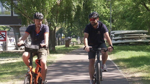 Zwei Männer fahren auf eine Radweg entlang.