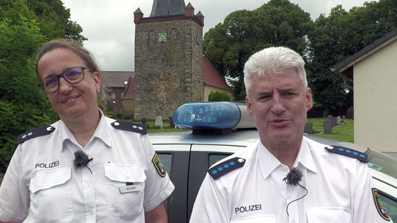 Zwei Polizeibeamte schauen in die Kamera.