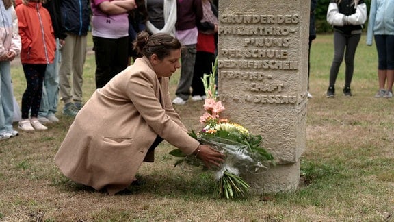 Blumen werden an einem Gedenkstein niedergelegt.