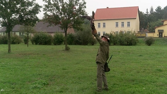 Ein Falkner mit einem Vogel auf dem Arm.