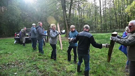 Holzstämme werden mittels Menschenkette weitergereicht.