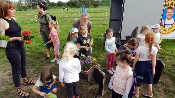 Kinder pflanzen Blumen in Kästen