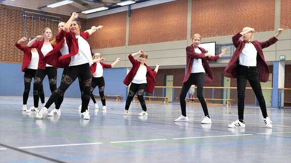 Jugendliche tanzen in einer Sporthalle