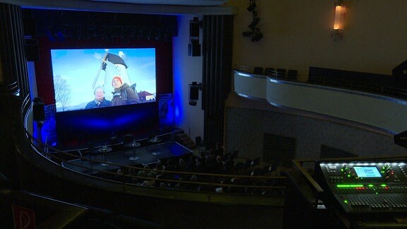 Blick in einen großen Kinosaal auf die Leinwand von einer Empore aus.