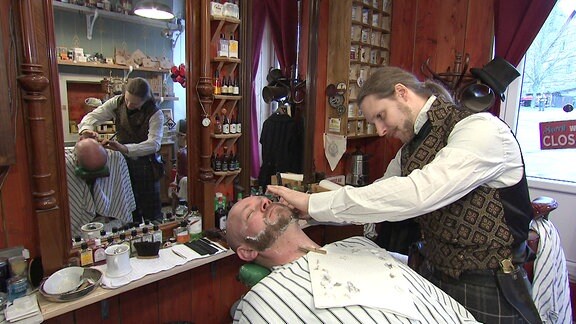 Mann rasiert einen anderen Mann